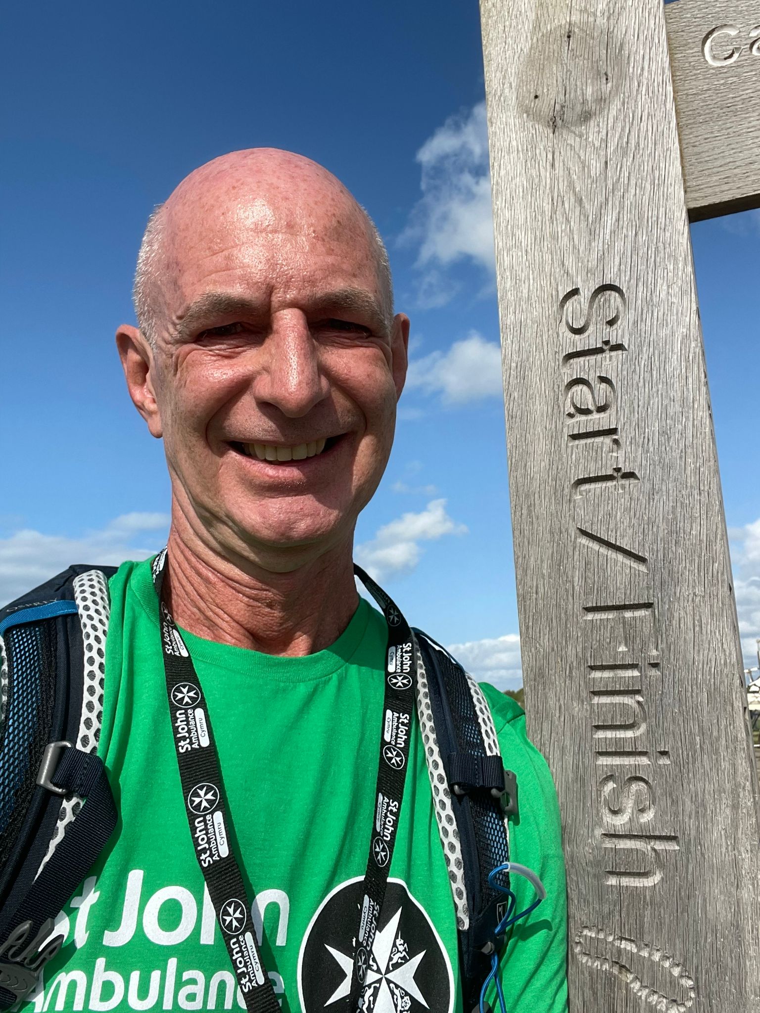 Eric Houlden, man standing next to wooden fingerpost waymarker sign on a footpath